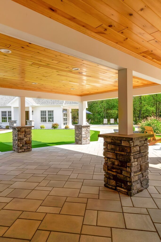 Covered patio with stone columns and cedar ceiling overlooking backyard in Clarence New York