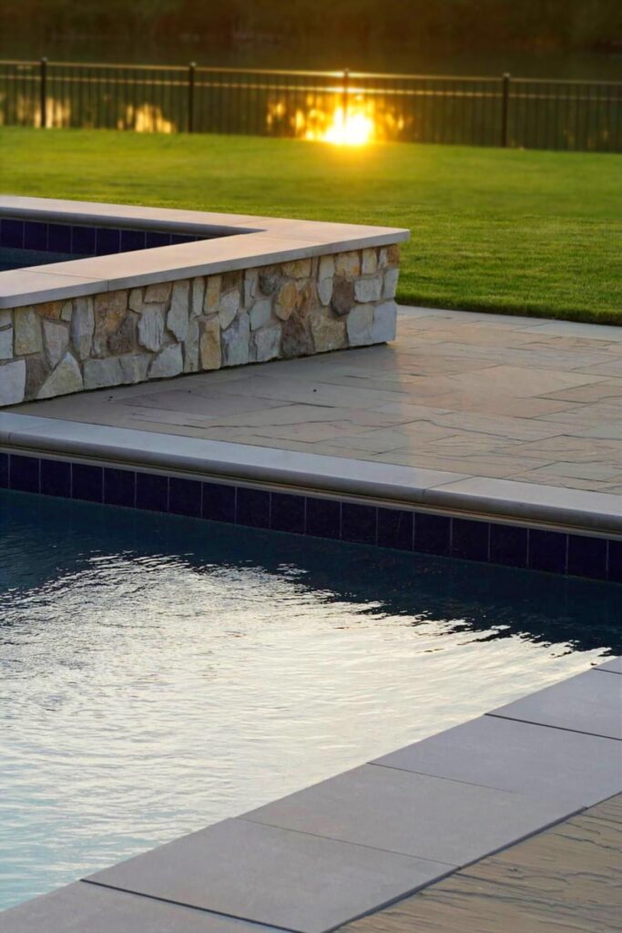 Custom pool and integrated hot tub with stone coping at sunset in Clarence New York backyard
