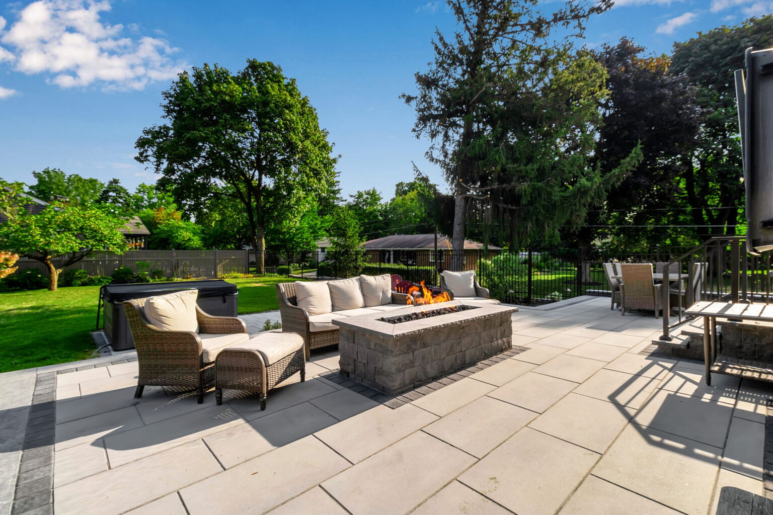 Custom stone patio with fire feature and outdoor seating designed by Lattimer Outdoor Living Spaces in Western New York