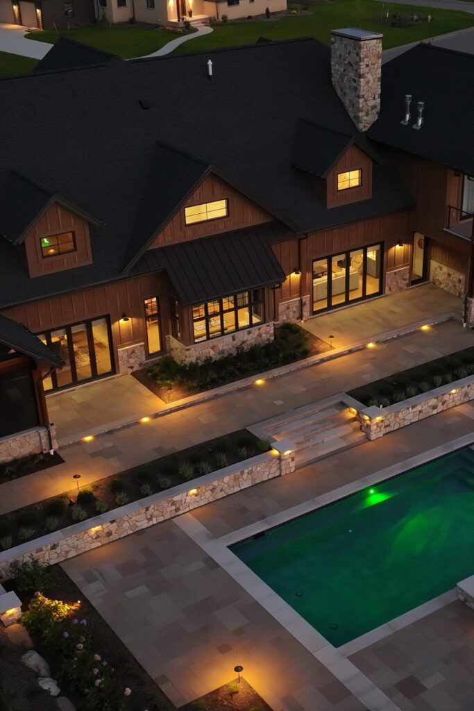 Aerial night view of luxury backyard with pool, patio lighting, and outdoor living spaces in Clarence New York