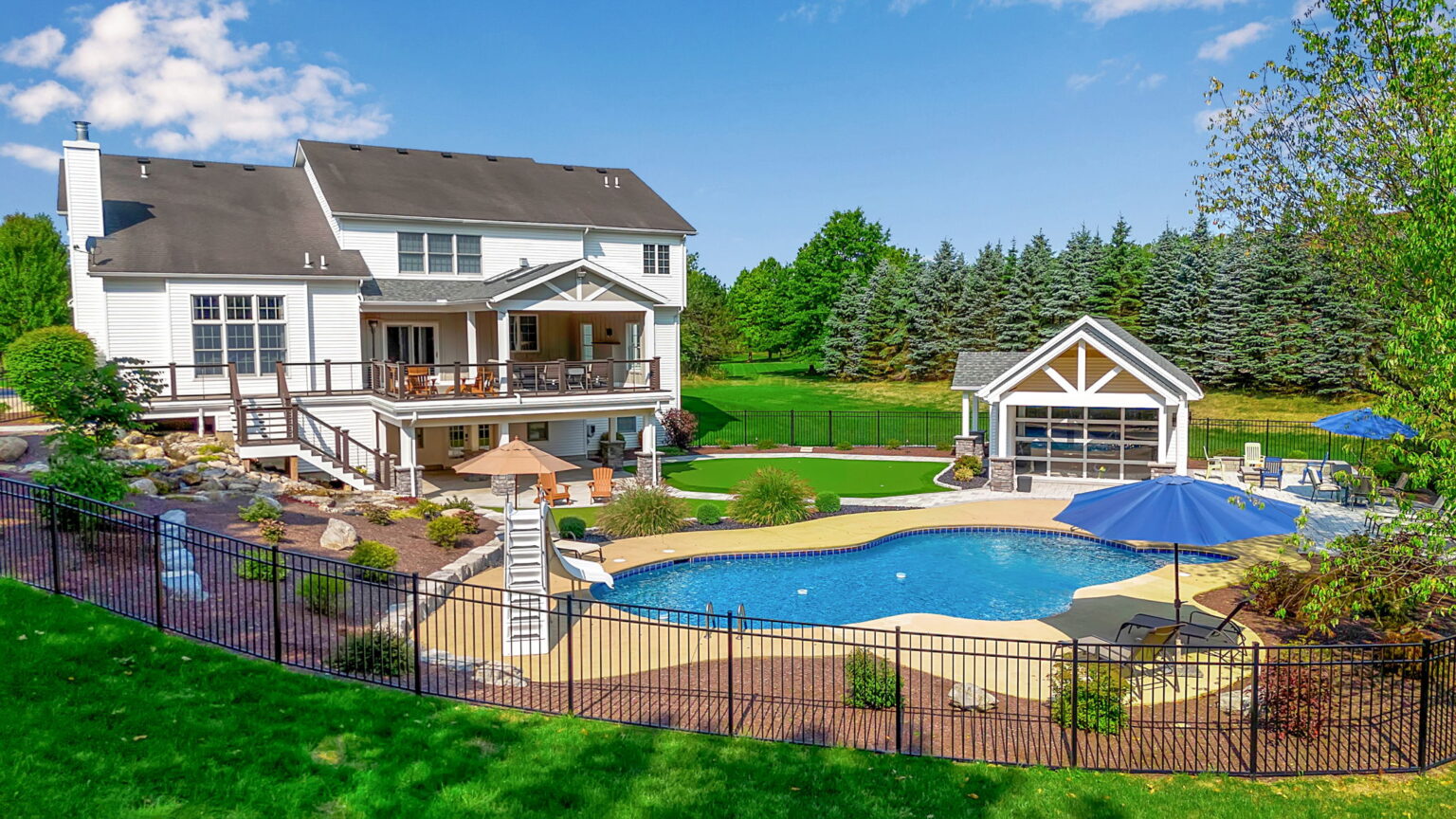 Aerial view of luxury backyard with multi-level deck, pool, and putting green in Clarence New York