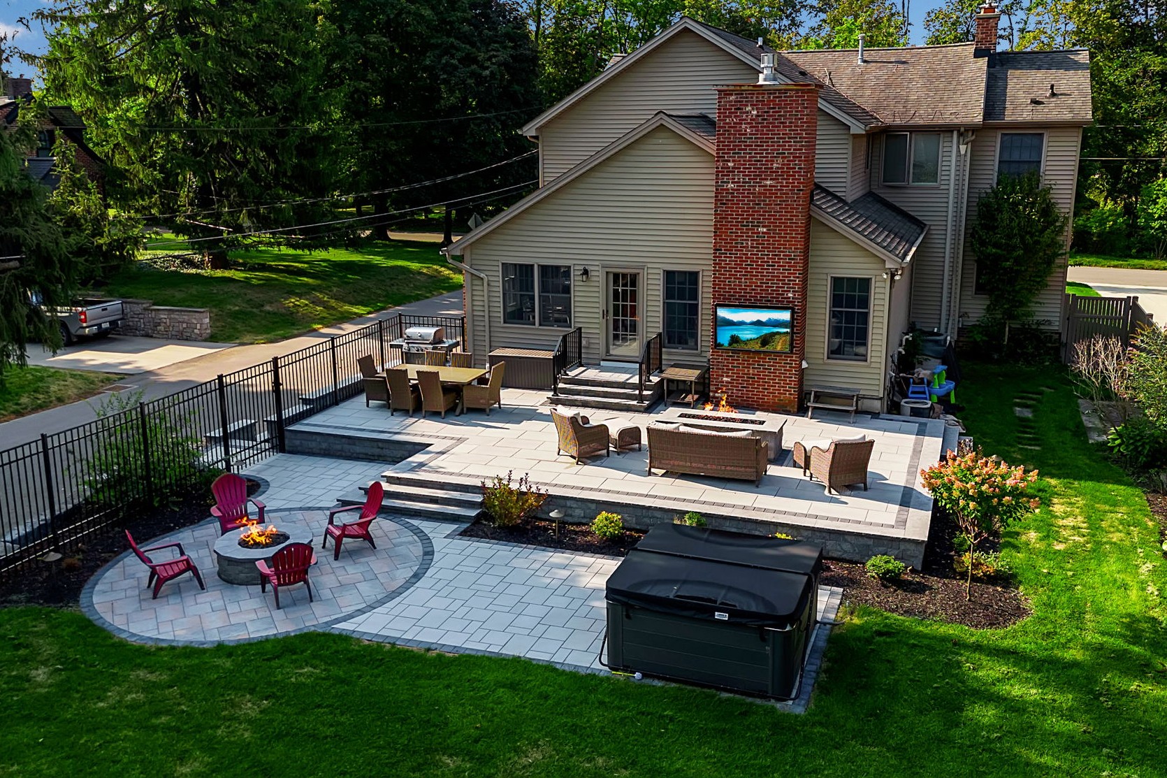 Custom multi-level backyard patio with fire pit and seating designed by Lattimer Outdoor Living Spaces in Western New York