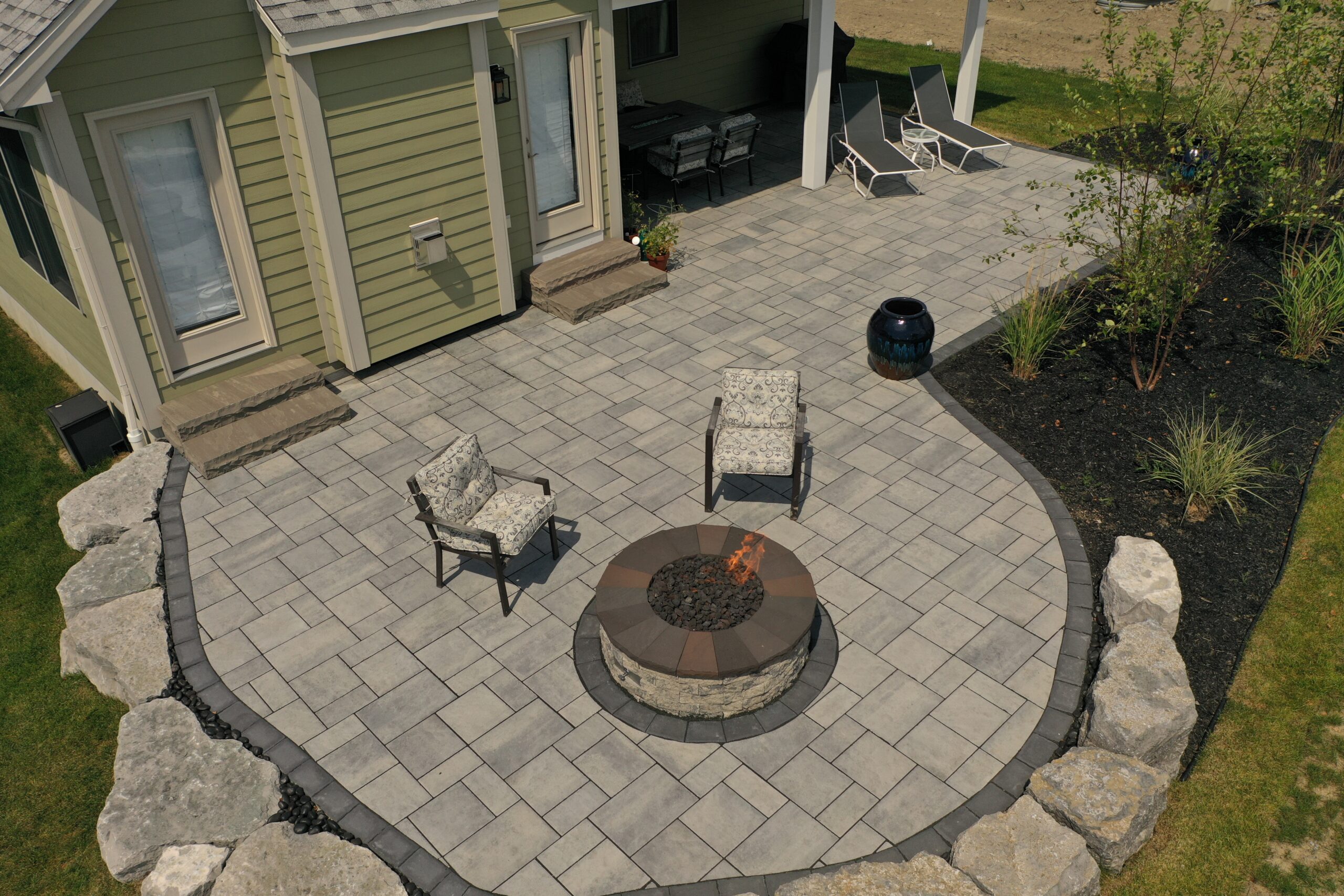 Circular stone patio with fire pit and seating designed by Lattimer Outdoor Living Spaces in Western New York