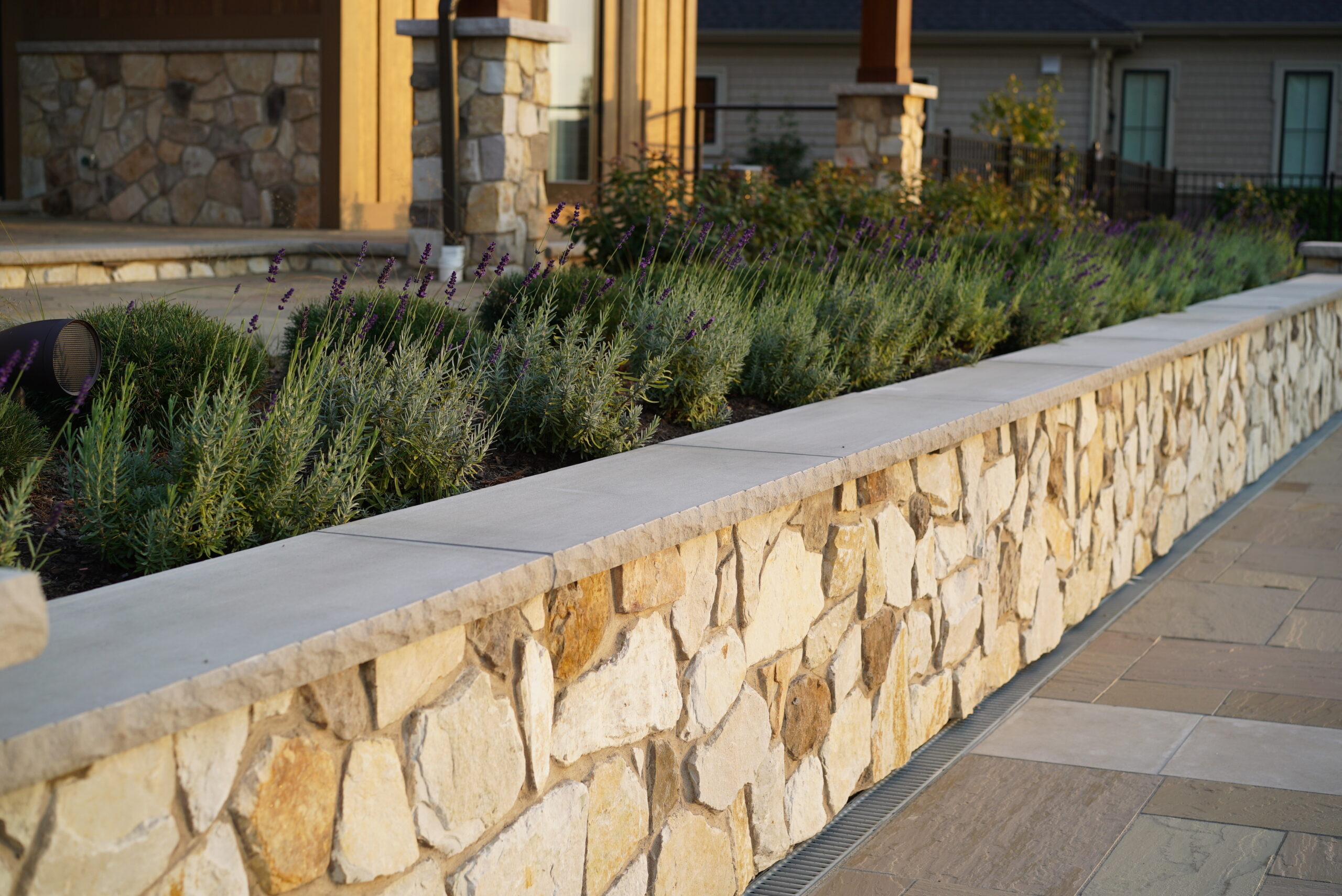 Natural stone retaining wall with landscaped planting bed in custom outdoor living space in Western New York