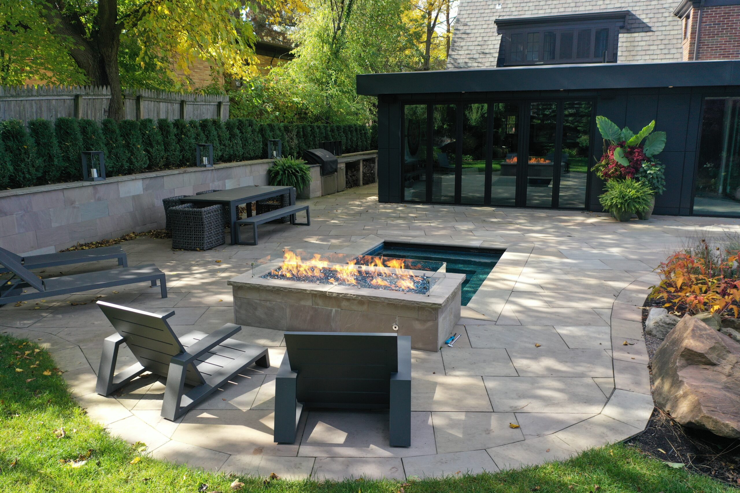 Modern custom patio with fire feature and stone pavers designed by Lattimer Outdoor Living Spaces in Western New York